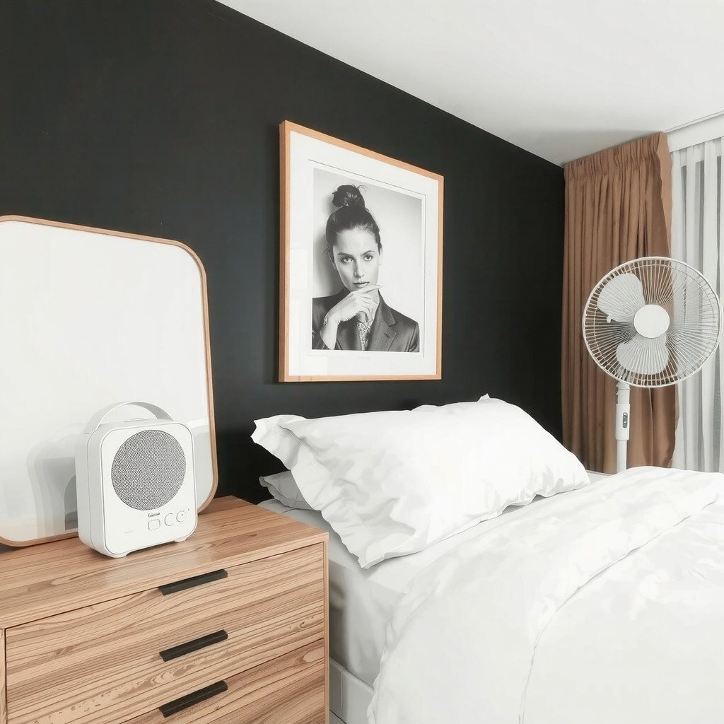 A bedroom with a white noise machine on a nightstand, and a fan in the corner