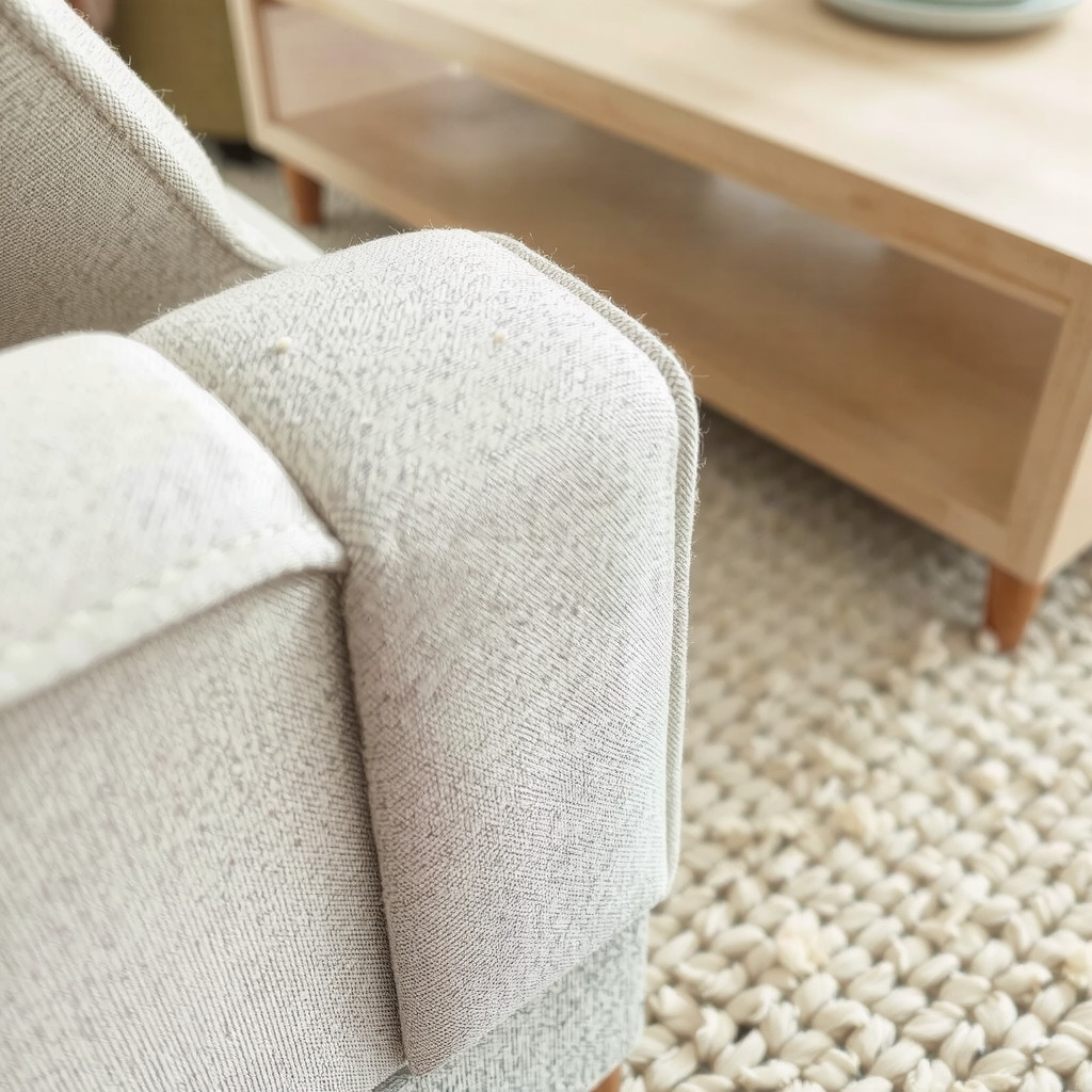 Close up detail of textured linen sofa fabric and light wood grain surface