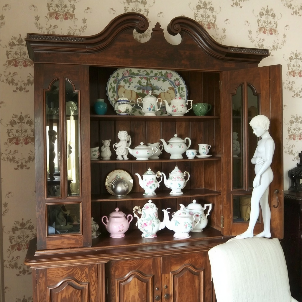 Antique china cabinet filled with vintage tea sets